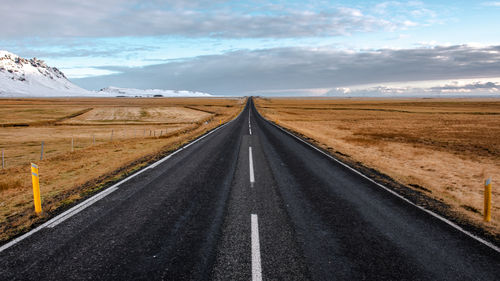 Empty road by mountain against sky