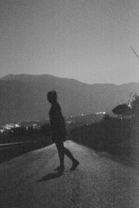 Side view of silhouette man walking on mountain against sky