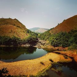 Scenic view of river by mountains against sky