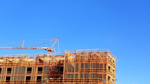 Low angle view of crane against clear blue sky