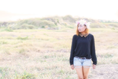 Young woman wearing floral wreath while standing on field