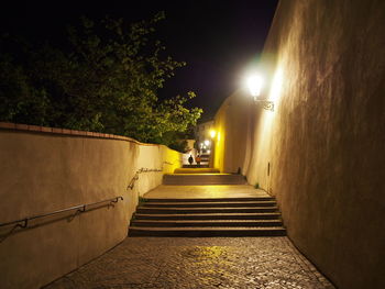 Empty alley amidst buildings at night