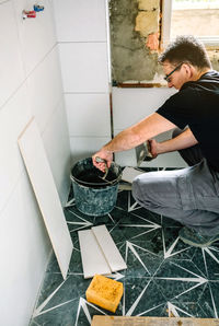 Male bricklayer taking cement from bucket