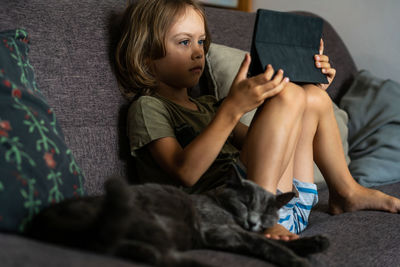 Boy using digital tablet computer playing games or watching cartoons at home.