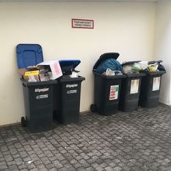 Garbage can on footpath against wall