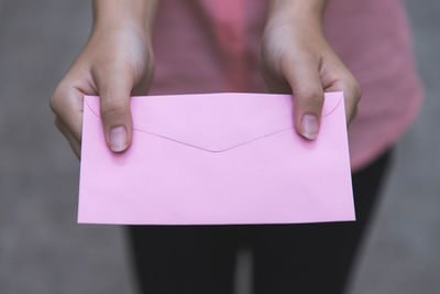 Midsection of woman giving pink envelope