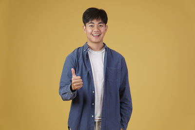 Portrait of smiling man standing against yellow background