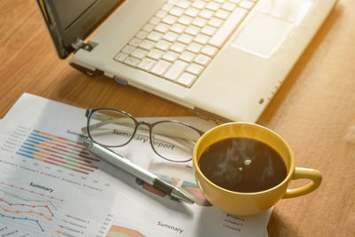 Coffee cup and laptop,chart,eyeglass and pen on table in business office