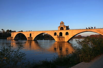 Arch bridge over river against clear sky