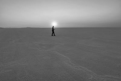 Silhouette person standing on sea shore against sky