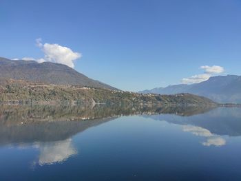 Scenic view of lake and mountains against blue sky