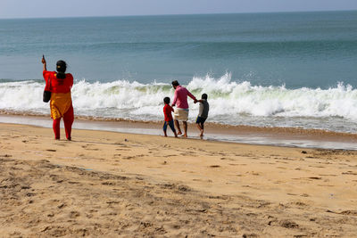 Rear view of people enjoying on beach