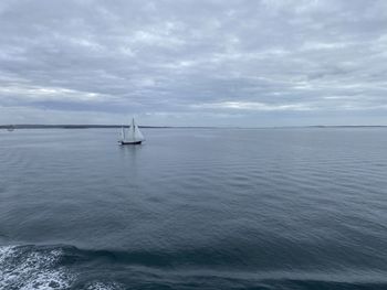 Sailboat sailing on the ocean against the grey sky