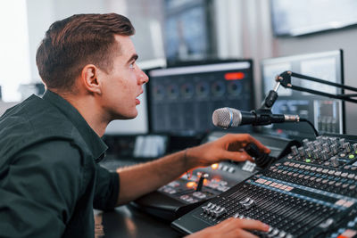 Young man is indoors in the radio studio is busy by broadcast.