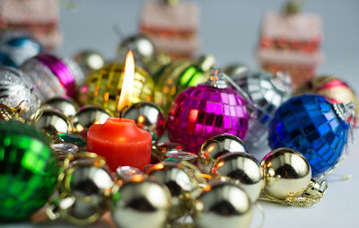 Close-up of lit candle amidst christmas decorations on table