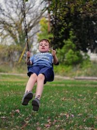 Full length of boy enjoying on swing at park