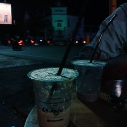 Midsection of man with drink on street at night