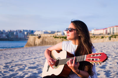 Young woman playing guitar at beach