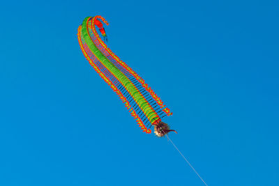 Low angle view of kite against clear blue sky