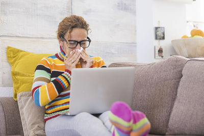 Woman using phone while sitting on sofa at home