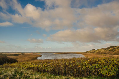 Scenic view of sea and landscape against cloudy sky