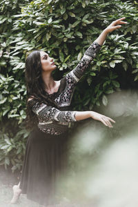 Young woman standing by tree