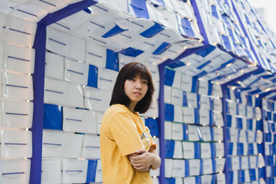 Portrait of young woman standing against wall