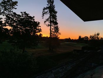 Silhouette trees on field against sky during sunset