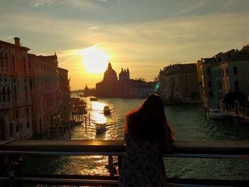 Rear view of woman standing in city at sunset