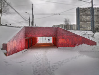 Wet road by trees against sky during winter