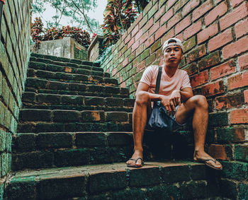 Man sitting on staircase against wall