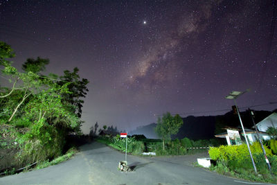 Road amidst trees against sky at night