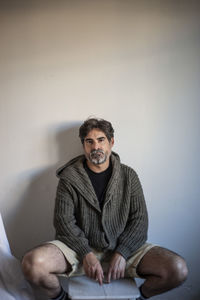 Portrait of smiling young man sitting against wall