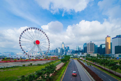 Ferris wheel in city against cloudy sky