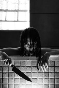 Portrait of woman sitting by window at home