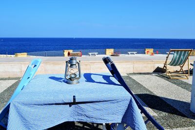 Lounge chairs on beach against clear blue sky