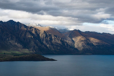 Scenic view of lake and mountains against cloudy sky