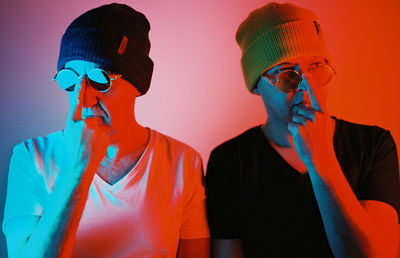 Portrait of men with sunglasses against orange wall 