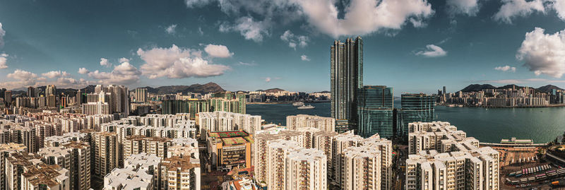 Panoramic view of city buildings against cloudy sky