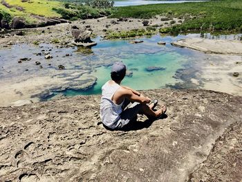 Rear view of man sitting on shore