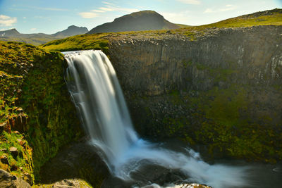 Scenic view of waterfall against mountain