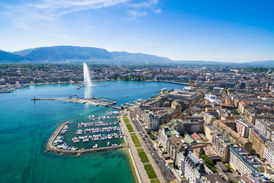 Aerial view of cityscape by sea against blue sky