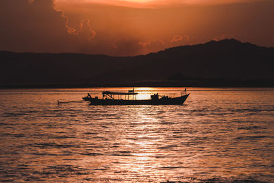 Silhouette boat in sea against sky during sunset