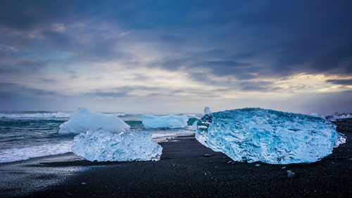 Snow covered land and sea against sky