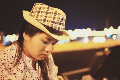 Portrait of young woman looking at illuminated camera at night