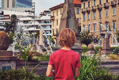 Rear view of man against buildings in city