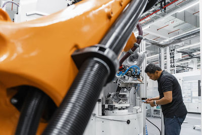 Maintenance engineer repairing robot arm in factory