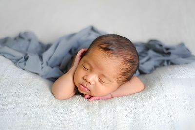 Portrait of cute baby boy lying on bed at home