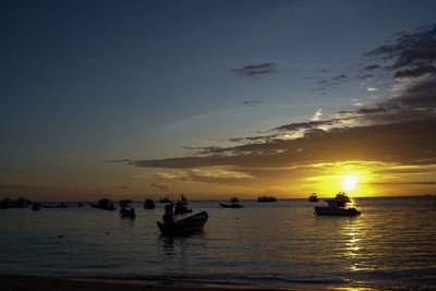 Silhouette boats in sea against sky during sunset