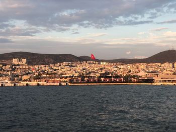 Sea by buildings in town against sky